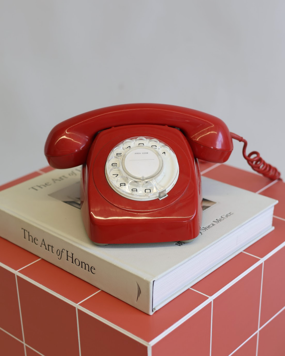 Red rotary telephone on The Art of Home book